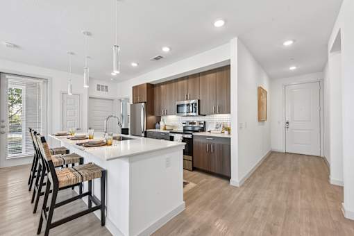 A modern kitchen with a white island and wooden floors.