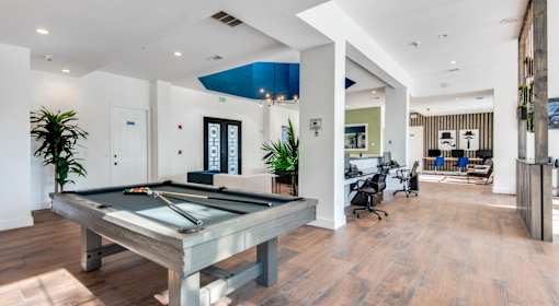 A pool table is in the middle of a room with a wooden floor.