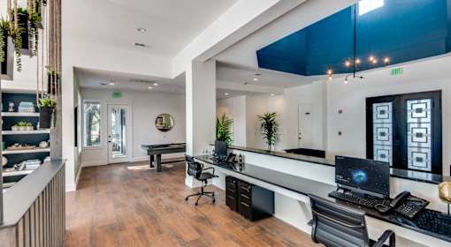 A modern office space with a long desk, chairs, and a computer.