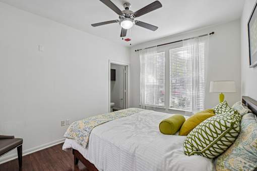 A bedroom with a bed, pillows, and a ceiling fan.