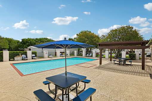 A pool with a table and chairs and an umbrella.
