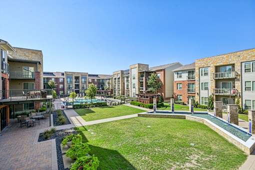 A sunny day at a residential complex with a grassy area and a small pool.