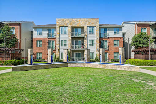 Apartment complex with a grassy front yard.