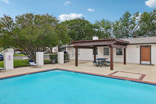 A pool with a table and chairs and a building in the background.