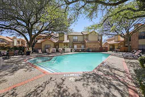 A pool surrounded by trees and houses.