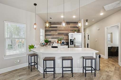 A kitchen with a white island and bar stools.
