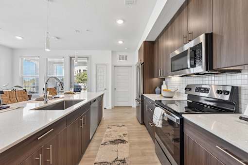 A modern kitchen with dark wood cabinets and stainless steel appliances.