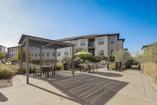 a patio with tables and chairs and a building in the background
