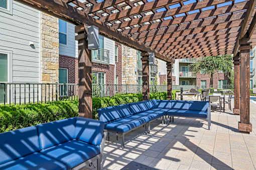 A row of blue benches are lined up under a wooden pergola.