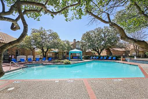 A swimming pool surrounded by trees and chairs.