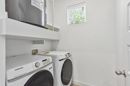 A white Samsung washing machine and dryer in a small laundry room.