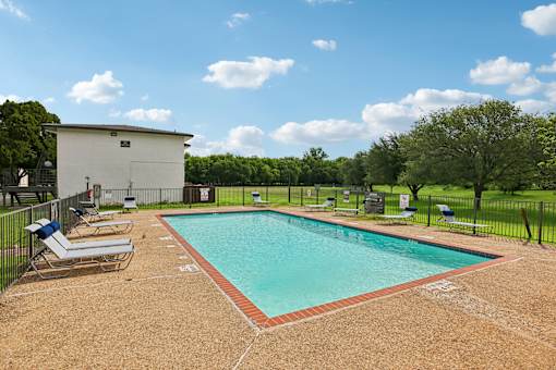 A small pool surrounded by a fence and chairs.