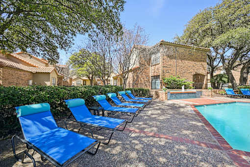 A pool surrounded by blue lounge chairs.