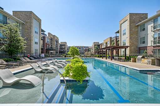 A pool surrounded by lounge chairs and buildings.