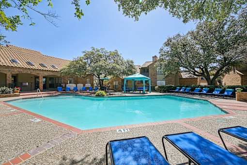 A pool surrounded by sun loungers and trees.