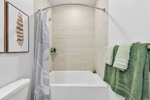 A white bathtub with a green towel hanging on the side.