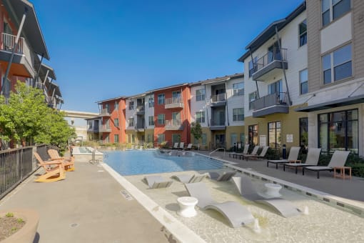 an apartment building with a pool and lounge chairs