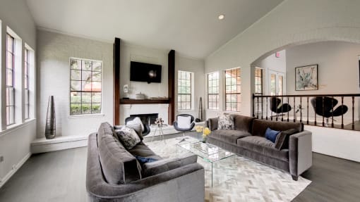 a living room with couches and a glass coffee table and a fireplace