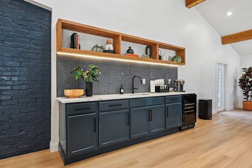 A kitchen with dark cabinets and a brick wall.