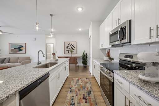 A modern kitchen with white cabinets and granite countertops.