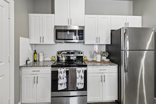 A modern kitchen with a stainless steel refrigerator, microwave, and oven.