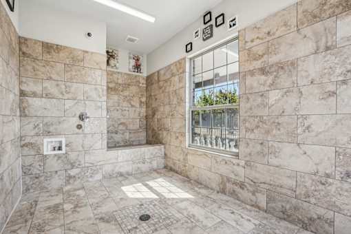 A bathroom with a marble tile shower and a window.