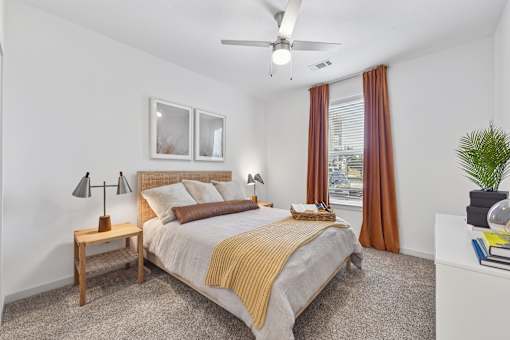 A bedroom with a bed, nightstand, and window.