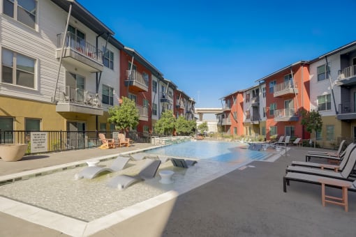 an apartment building with a pool and chairs in front of it