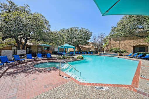 A pool area with a hot tub and lounge chairs.