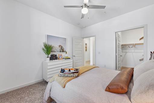 A bedroom with a bed, a ceiling fan, and a mirror.