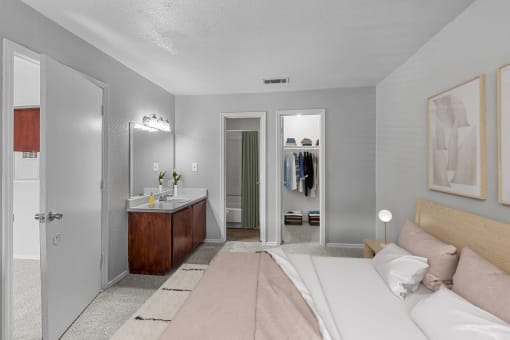 a bedroom with a bed and a bathroom with a sink and a mirror