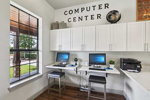 A computer center with two computers and a printer.