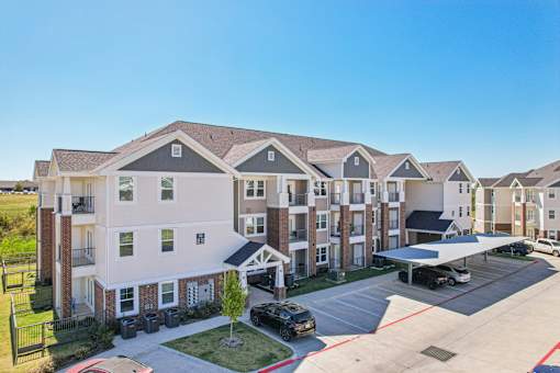 A large apartment complex with a parking lot in front.
