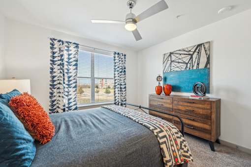 A bedroom with a bed, a dresser, and a painting on the wall.