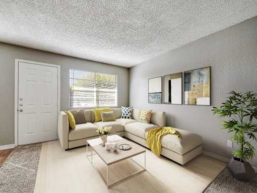 A living room with a white couch, a coffee table, and a potted plant.