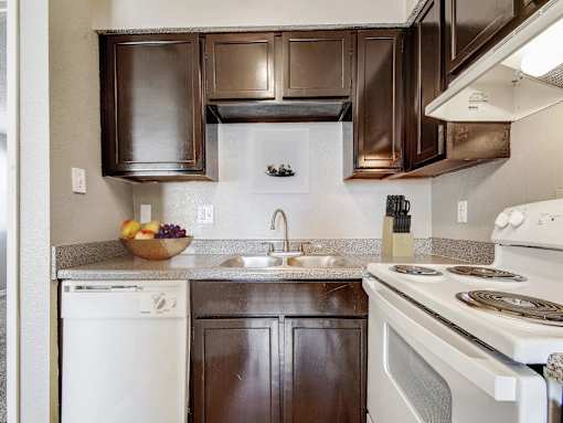 A kitchen with brown cabinets and white appliances.