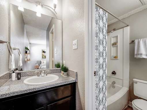 A bathroom with a sink, mirror, and shower.