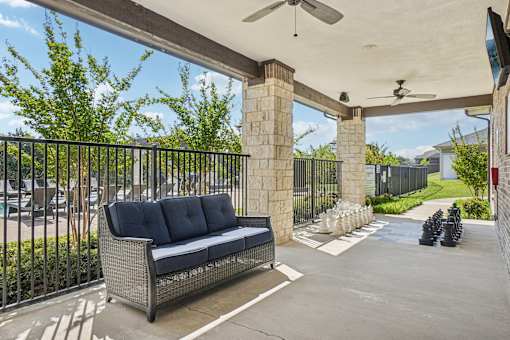 A black sofa sits on a patio under a white awning.