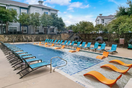 a swimming pool with blue chairs and yellow and orange chairs