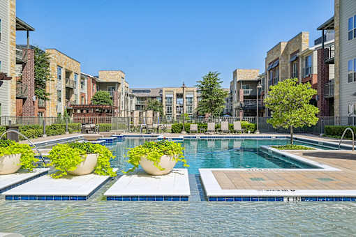 A swimming pool surrounded by buildings and potted plants.