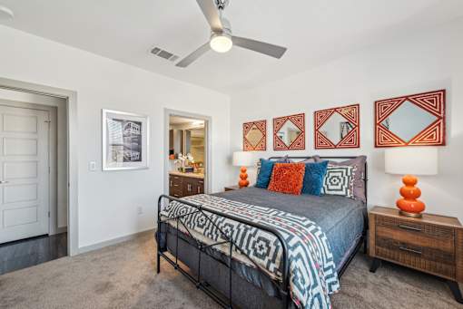 A bedroom with a bed, a dresser, and a ceiling fan.