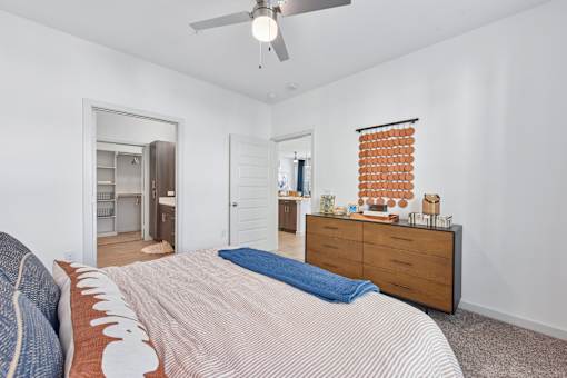 A bedroom with a bed, dresser, and ceiling fan.