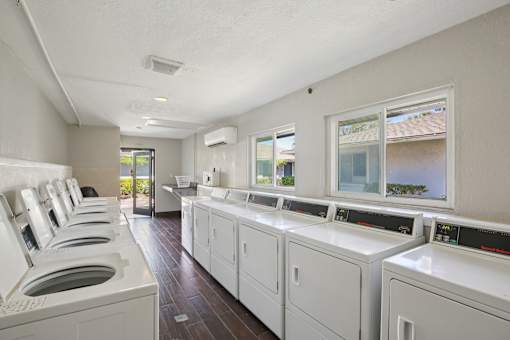 A row of washing machines are lined up in a laundry room.