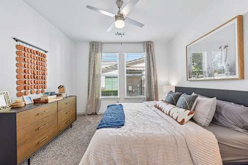 A bedroom with a large bed, a dresser, and a ceiling fan.
