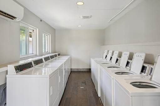 A row of white washing machines in a laundromat.