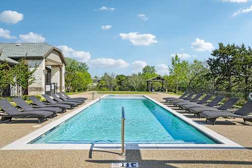 A large rectangular pool with a diving board in the middle surrounded by lounge chairs.