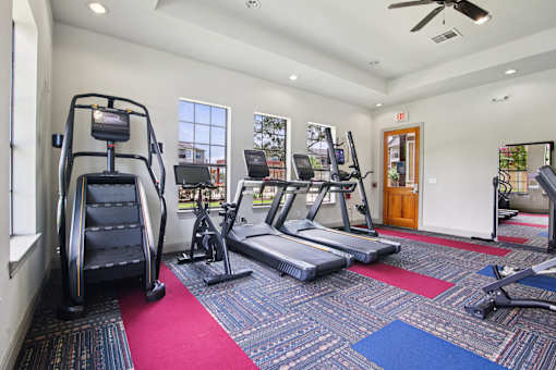 A gym with a variety of equipment including treadmills, elliptical machines, and a weight bench.