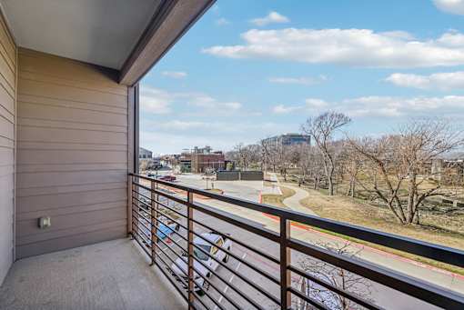 A balcony with a view of a road and trees.