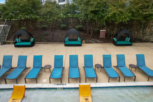 a row of blue and green chairs on the side of a pool