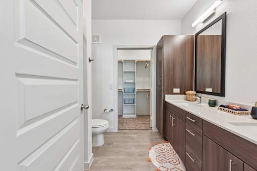 A bathroom with a white door and brown cabinets.